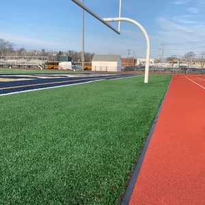 ACO Sport Precast Elastic Curbing System separating a synthetic turf football playing field and track surface