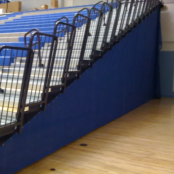 blue mesh bleacher enclosures by sportsfield specialties installed at high school gymnasium