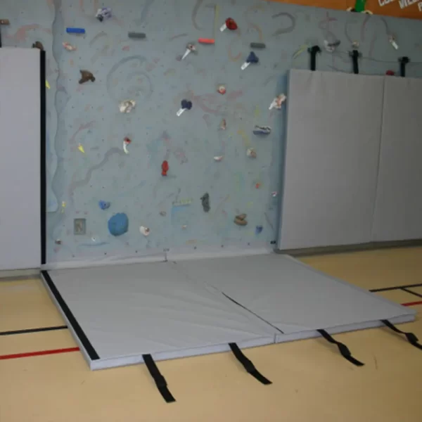 gray climbing wall mats by sportsfield specialties hooked to the climbing wall protecting gym users from hitting climbing holds