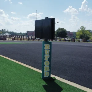 a delay of game clock installed on the side of a synthetic turf playing field with a delay of game clock mounting system