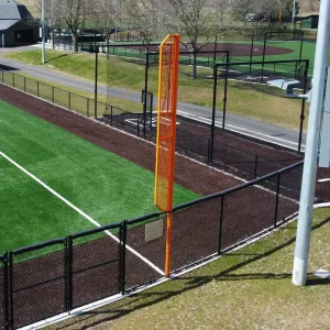 an orange foul pole with wing installed down the baseline of a synthetic turf playing field