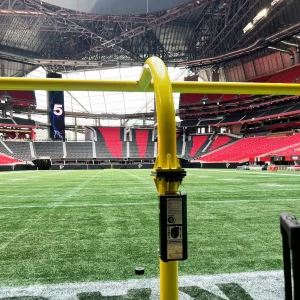 looking through a ground sleeve gooseneck hinged football goal post at the end of a football field