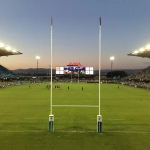 a ground sleeve rugby goal post installed at Avaya stadium with a game going on in the background