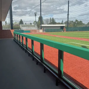 a green vinyl wrapped guard rail system installed in front of an enclosed dugout