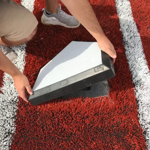 A sportsfield specialties sales rep installing a homeplate in a newly installed home plate forming system
