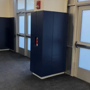 blue indoor column padding installed at athletic facility with cutouts for emergency alarms