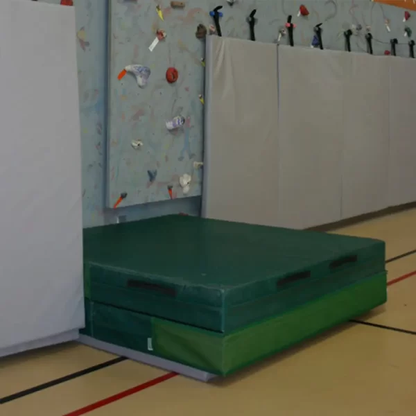 Landing zone mat by sportsfield specialties laid on floor below climbing wall ready for climbers