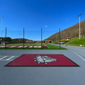 a maroon mesh sand pit cover installed on a long triple jump sand pit - includes digitally printed graphic in the center