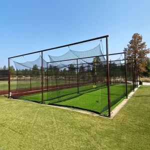 a two tunnel overhead batting tunnel installed in the practice area of a natural grass playing field