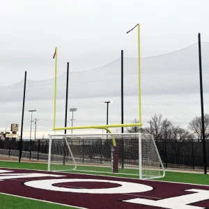 a plate mount football goal installed behind a soccer goal at the end of a synthetic turf multi-purpose athletic field