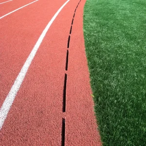 a precast slot drainage system installed down the side of a track surface to prevent water run off from flooding the synthetic turf playing surface