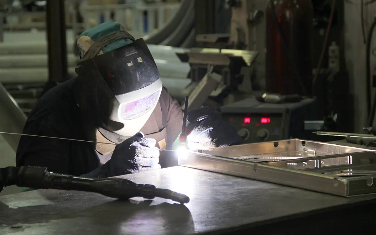 A welder welding an aluminum frame together in the sportsfield specialties manufacturing facility