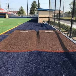 turf covered portable bullpen pitching mounds on the side of the playing field ready to be moved as needed.