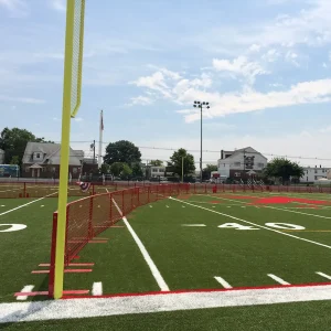 a red portable fence system sitting on a multi-purpose playing field setup for a baseball game