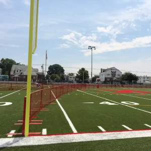 red seasonal fencing installed on a synthetic tuff playing field intended as a temporary outfield wall