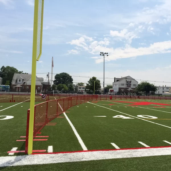 red seasonal fencing installed on a synthetic tuff playing field intended as a temporary outfield wall