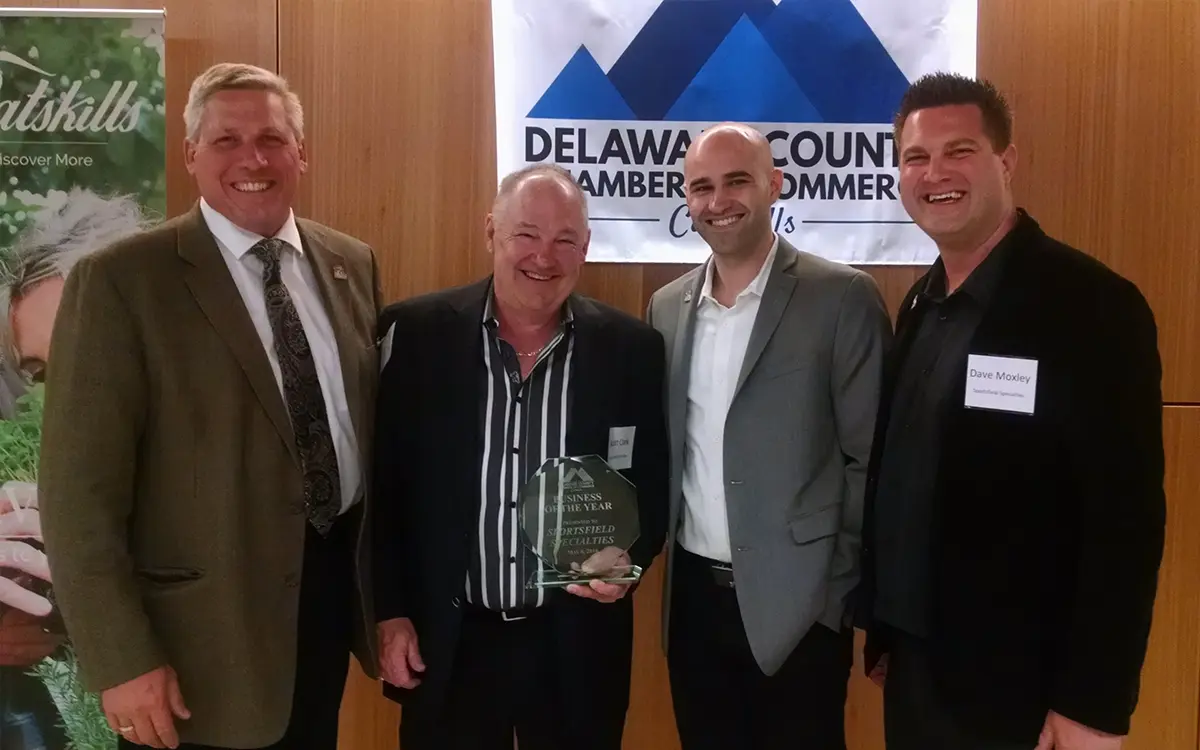 Wayne Oliver, Scott Clark, Sean Clark, and David Moxley standing with the 2016 Business of the Year Award from the Delaware County Chamber of Commerce