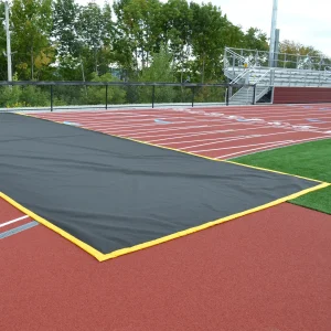 a track crossing mat laid across a running track. the mat has yellow trim.